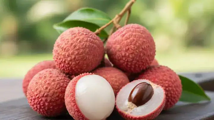 Grappe de litchis rouges avec un fruit pelé montrant la chair blanche translucide.