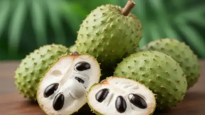 Gros fruit corossol vert à épines souples avec une tranche de chair blanche fibreuse.